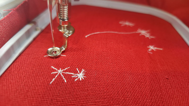 An image of the embroidery machine while it embroiders a random starscape.