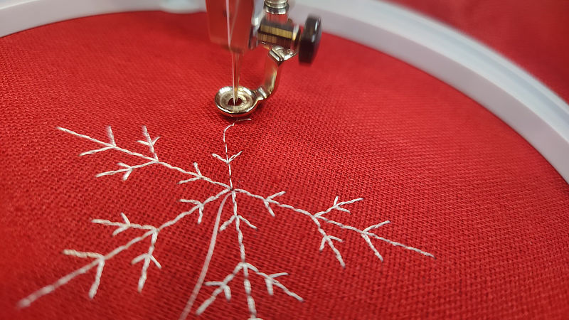An action shot of the embroidery machine making a snowflake.